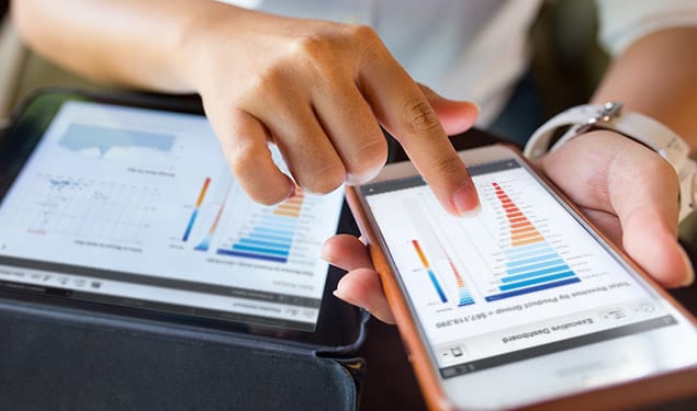 Person interacting with data visualizations and graphs on a smartphone and tablet.