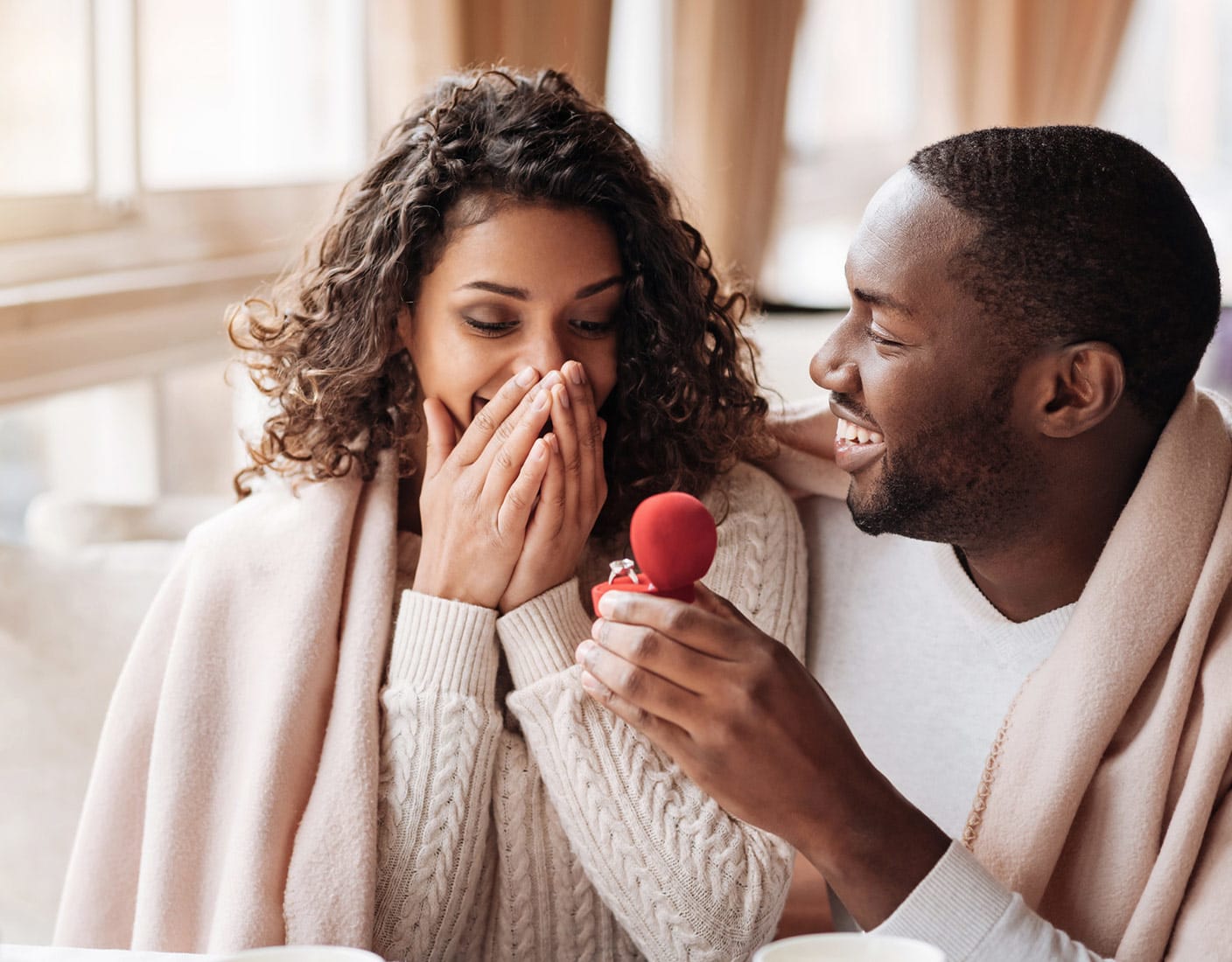A man surprises a woman by presenting her with a ring, symbolizing their love and connection.