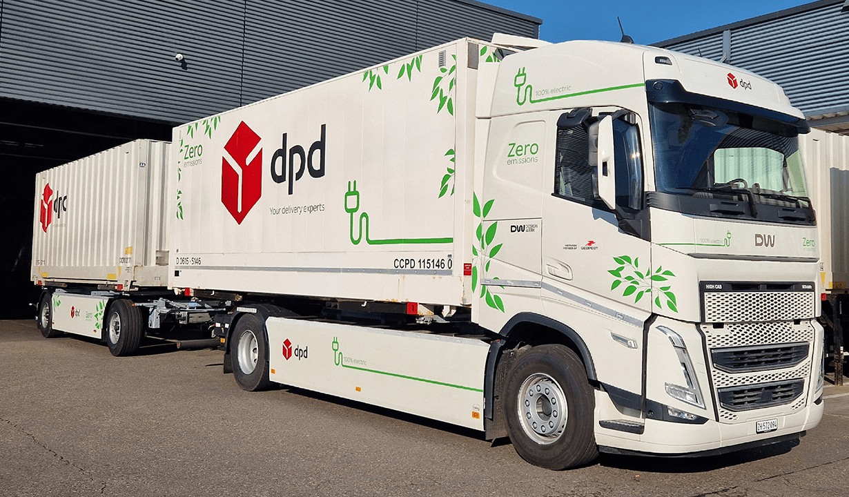 A large white truck featuring a prominent logo on its side, parked in an outdoor setting.