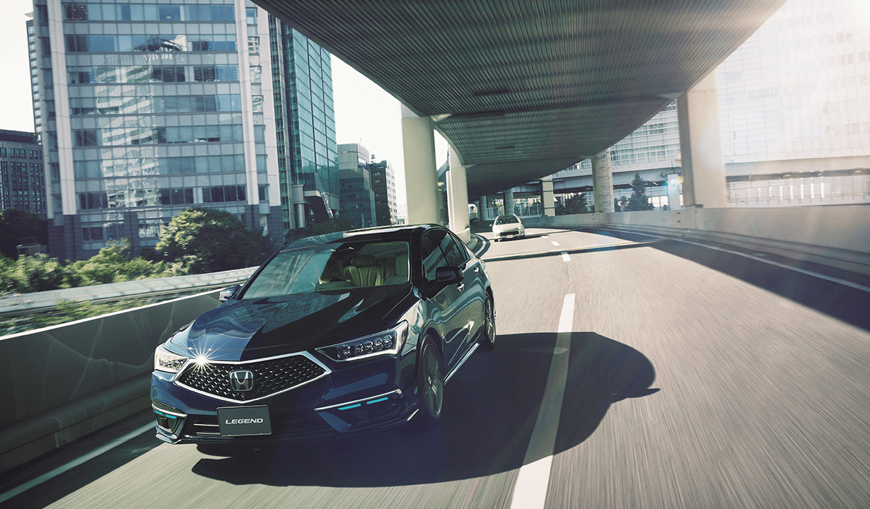 A new car drives smoothly along a bustling city street, showcasing its sleek design against an urban backdrop.