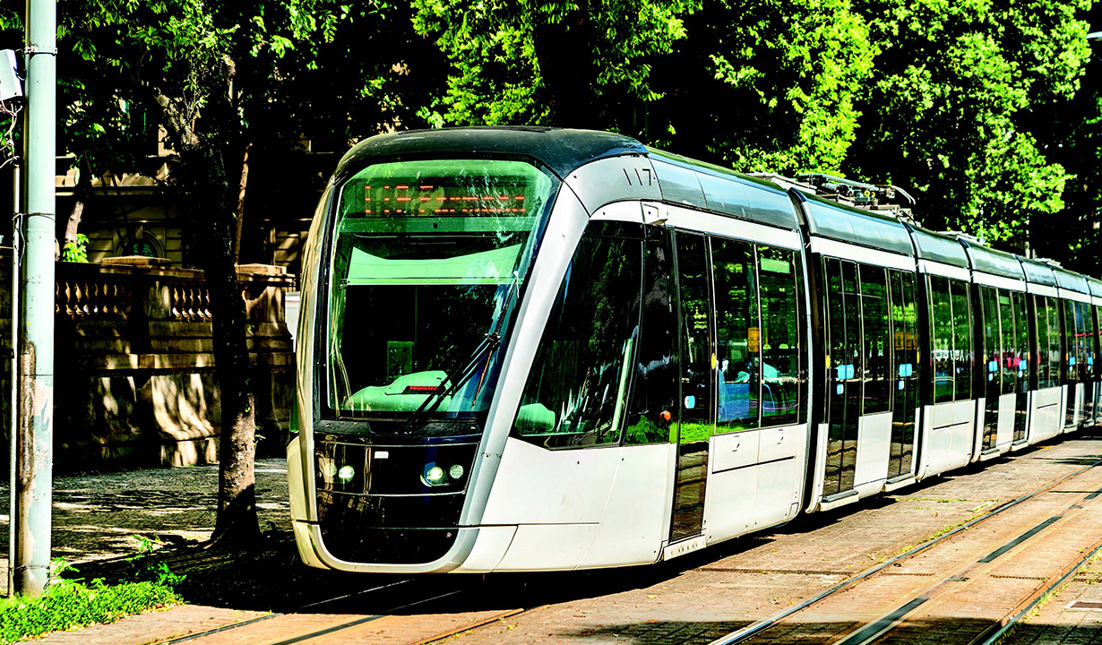 A train moves along the tracks through an urban landscape.