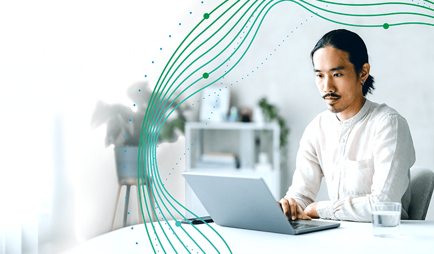 Image of a man sitting at a table working on a laptop
